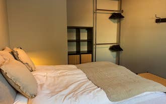 A bedroom featuring a queen-sized bed and an open closet with hangers on one wall.