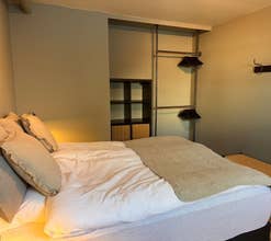 Une chambre avec un lit queen-size et une penderie ouverte avec des cintres sur un mur.