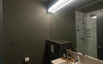 Modern bathroom with a large mirror, a minimalist sink, and a tiled shower area at AK-Lux101 in Akureyri.