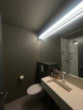 Moderne bad med stort speil, minimalistisk servant og flislagt dusj på AK-Lux101 i Akureyri.