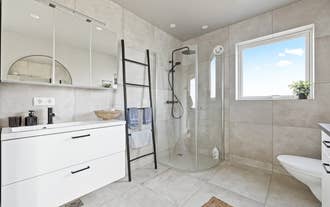 The bathroom at Serene Summerhouse Near Selfoss features a walk-in shower and sleek black fixtures.