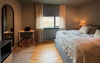 Stylish bedroom with a large bed, full-length mirror, and a small wooden desk at AK-Lux201 in Akureyri.