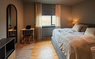 Stylish bedroom with a large bed, full-length mirror, and a small wooden desk at AK-Lux201 in Akureyri.