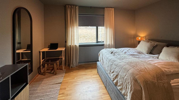 Stylish bedroom with a large bed, full-length mirror, and a small wooden desk at AK-Lux201 in Akureyri.