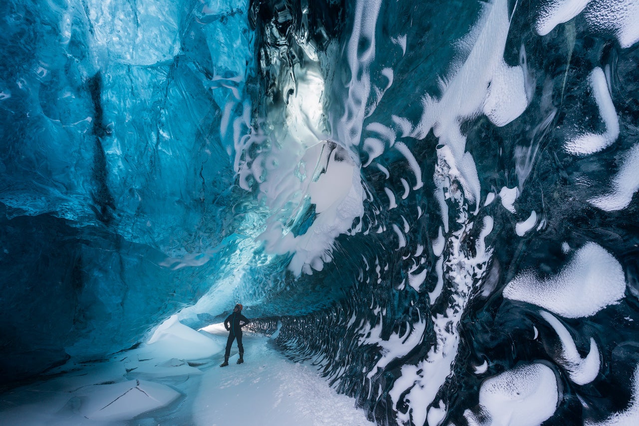 Eine Person erkundet im Winter eine atemberaubende blaue Eishöhle im Vatnajökull-Gletscher an der Südküste Islands.