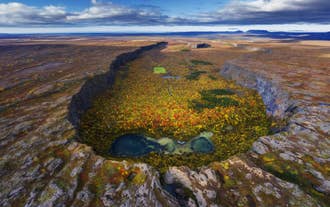 De Ásbyrgi kloof in Noord-IJsland is bedekt met levendige herfstkleuren en wordt omringd door kliffen en natuurlijke poelen.