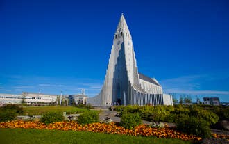 La chiesa Hallgrimskirkja a Reykjavik si erge imponente sotto un cielo azzurro e limpido, circondata da vivaci fiori estivi.