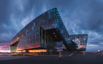 La Sala Concerti Harpa di Reykjavik si illumina al tramonto, con la sua facciata di vetro che riflette i colori del cielo serale