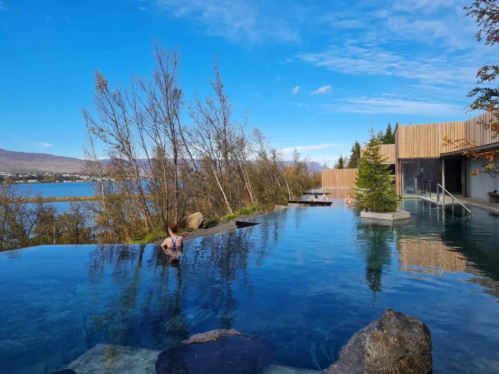 Visitor relaxes in the Forest Lagoon infinity pool overlooking Eyjafjordur Fjord.