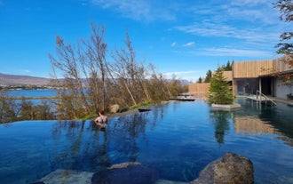 Visitor relaxes in the Forest Lagoon infinity pool overlooking Eyjafjordur Fjord.