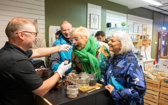 A shopkeeper offers a woman a sample of local jam during the Reykjavik Harbor Food Tour.