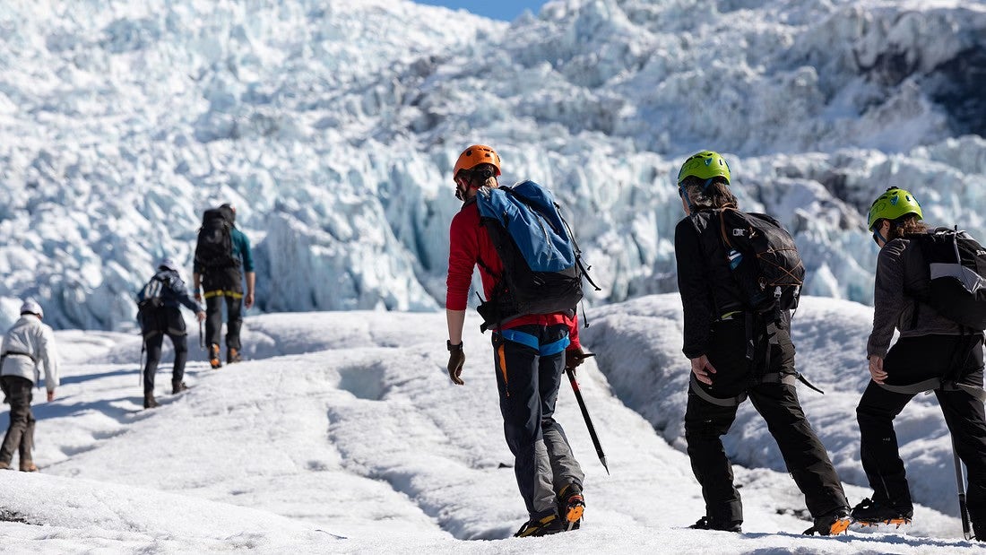 Three hikers hike on the massive icey field of Solheimajokull Glacier as part of a South Coast tour.