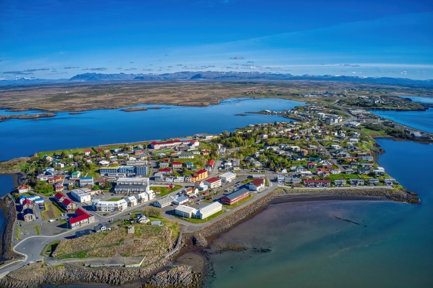 Farverige huse og maleriske kystudsigter i Borgarnes, Vestisland, med bjerge og skyer i baggrunden.