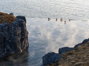 A group of travelers enjoying the ocean views from the Sky Lagoon in Iceland.