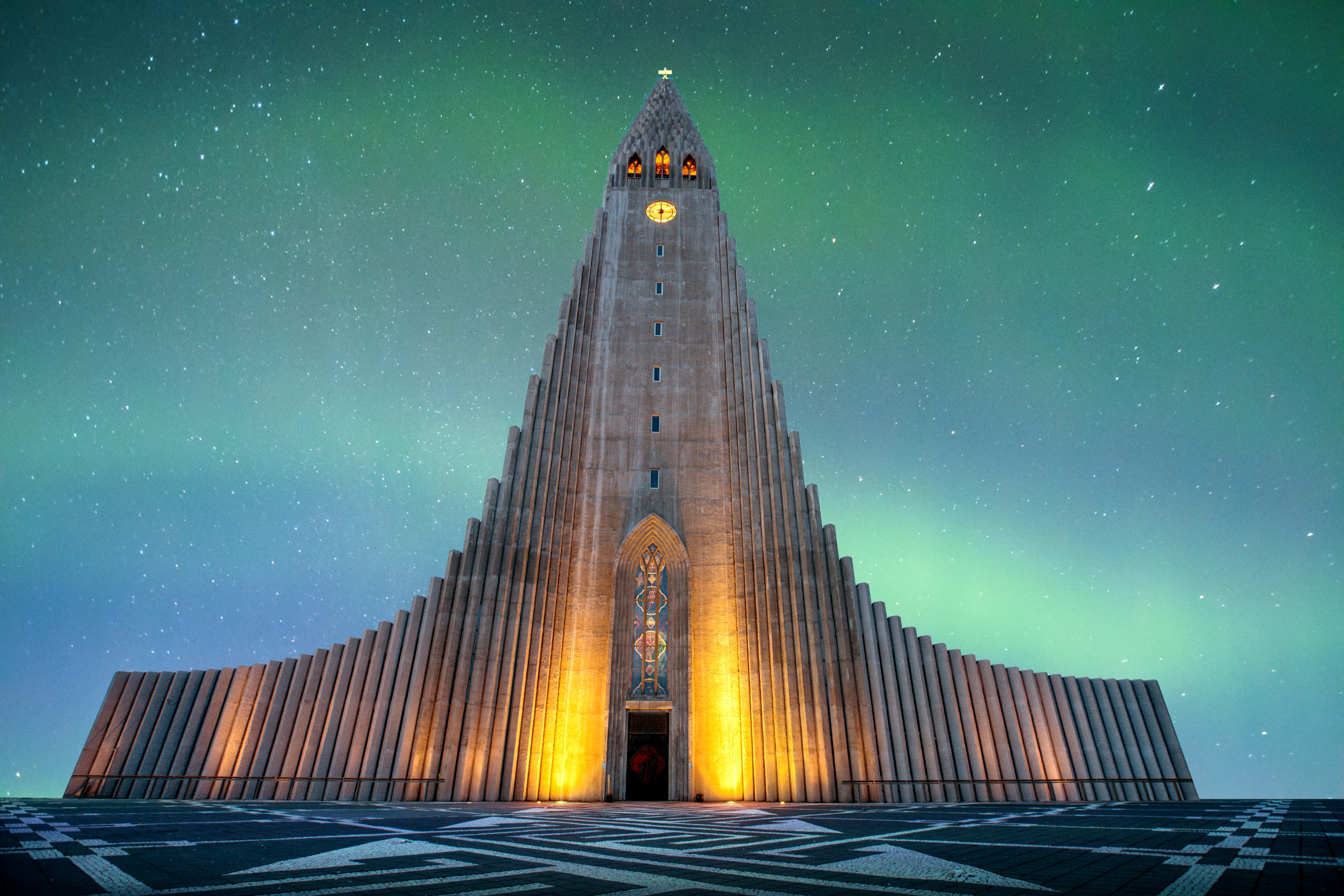 Kościół Hallgrimskirkja rozświetlony pod zorzami polarnymi w Reykjaviku podczas bezchmurnej zimowej nocy.