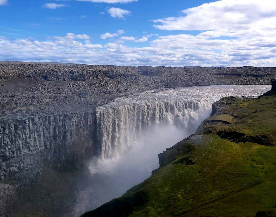 Dettifoss-waterval in Noord-IJsland die in een diepe kloof stroomt onder een heldere blauwe lucht.