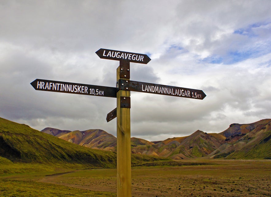 A Laugavegur Trail signpost pointing to the trail directions to Hrafntinnusker Mountain Peak and Landmannalaugar.