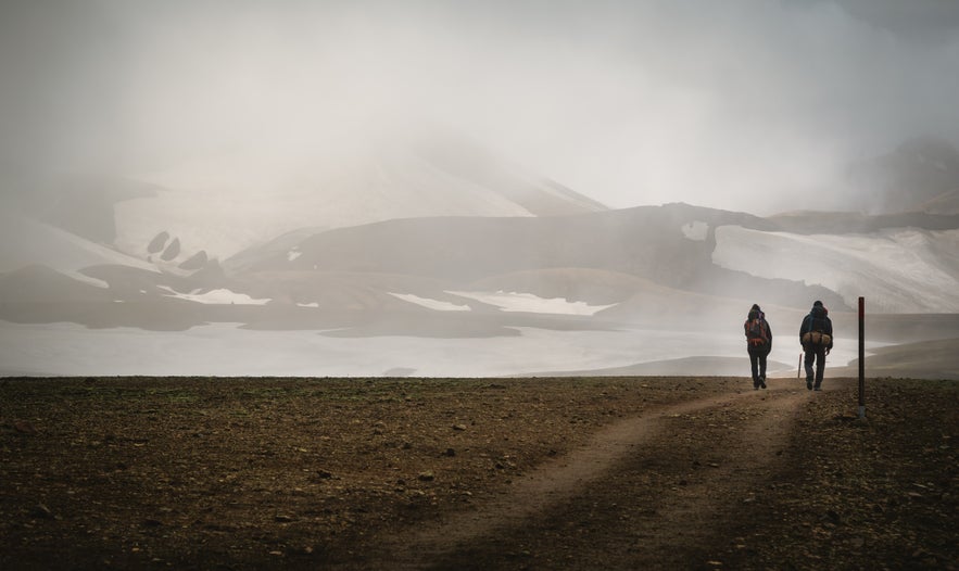 Two hikers trekking towards the Hrafntinnusker Mountain Peak in Iceland’s Highlands.