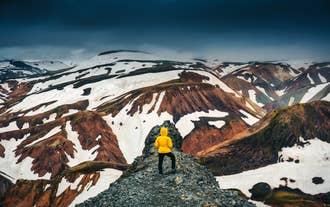 En vandrer nyder de sneklædte bjerge i Landmannalaugar i Island.