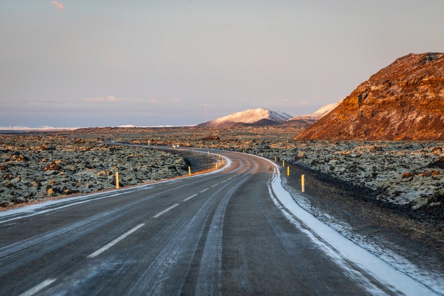 Winter road leading to Grindavik, Iceland, with lava fields and snow-covered mountains in the Reykjanes Peninsula.