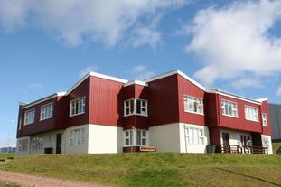 Exterior view of Framtid Apartments and Holiday Homes with a red upper level and white lower level with grass out the front.