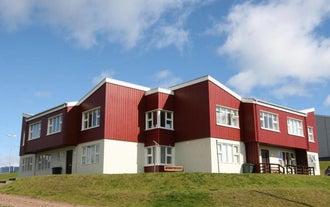 Exterior view of Framtid Apartments and Holiday Homes with a red upper level and white lower level with grass out the front.