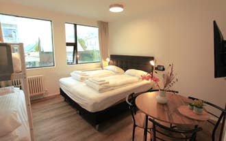 A cozy double room at Day Dream L23 Guesthouse features a black bed frame, soft lighting, large windows, and a wooden table with