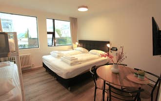 A cozy double room at Day Dream L23 Guesthouse features a black bed frame, soft lighting, large windows, and a wooden table with
