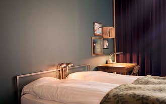 Cozy bedroom at Kex Thingeyri in the Westfjords with a bed and desk lamp.