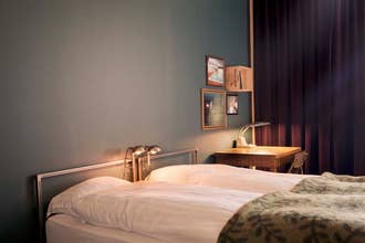 Cozy bedroom at Kex Thingeyri in the Westfjords with a bed and desk lamp.