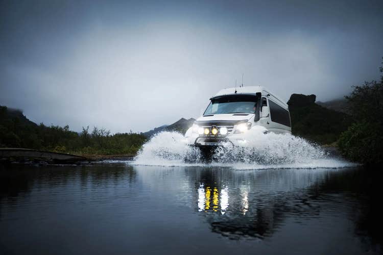 Super jeep splashing through river crossing in rugged landscape in Iceland's South Coast.