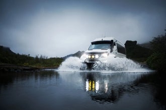 Super jeep splashing through river crossing in rugged landscape in Iceland's South Coast.
