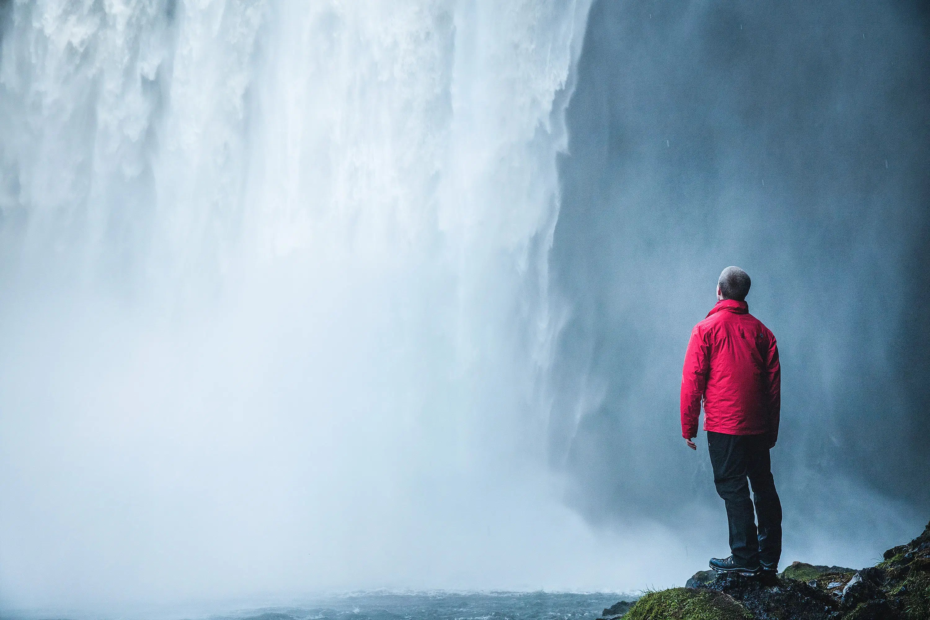 Traveler standing near Skogafoss Waterfall on Iceland's South Coast.