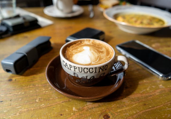 A warm cup of cappuccino on a wooden table in a cafe in Vik, Iceland.