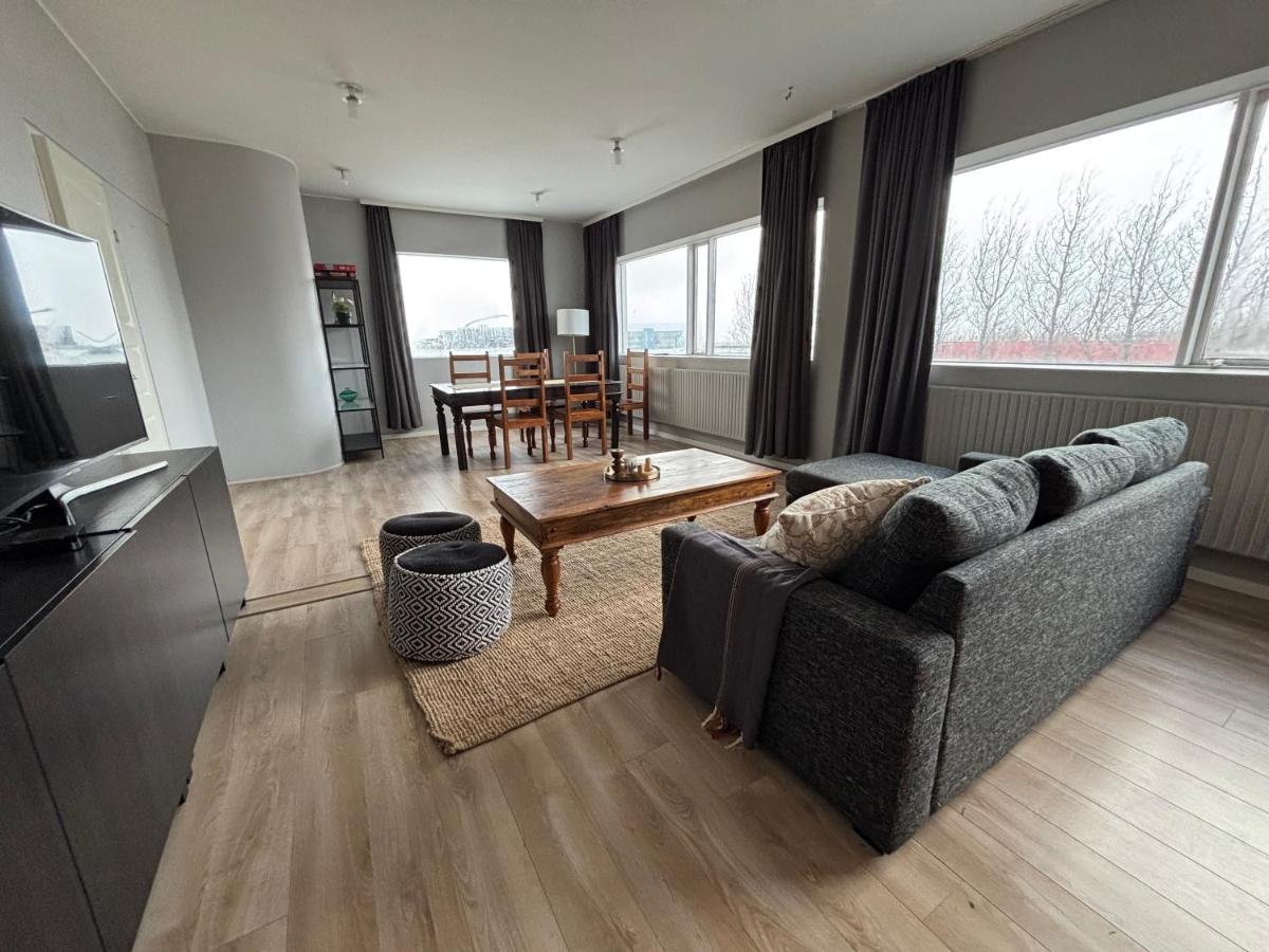 Geräumiges Wohnzimmer im Heima at Selfoss Apartment mit grauem Sofa, Holzcouchtisch und Essbereich.
