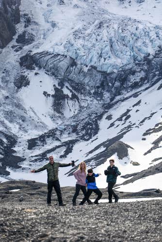 A family poses in front of snowy mountains during their tour of Thorsmork in Iceland.