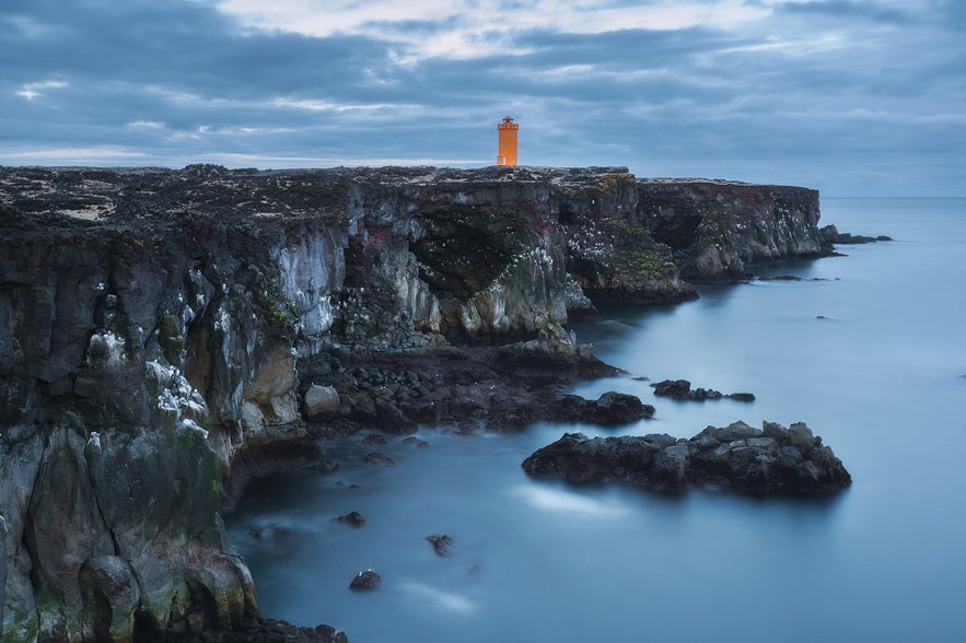 Incredible Svortuloft Cliffs on the Snaefellsnes Peninsula with an orange lighthouse in Iceland