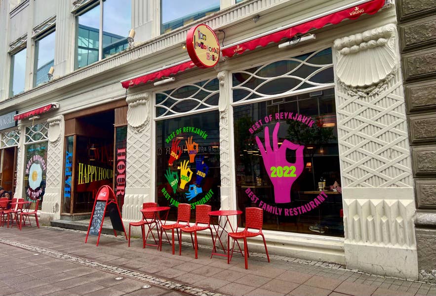 Exterior of Laundromat Cafe in downtown Reykjavik with colorful windows, red chairs, and street seating on Austurstraeti.