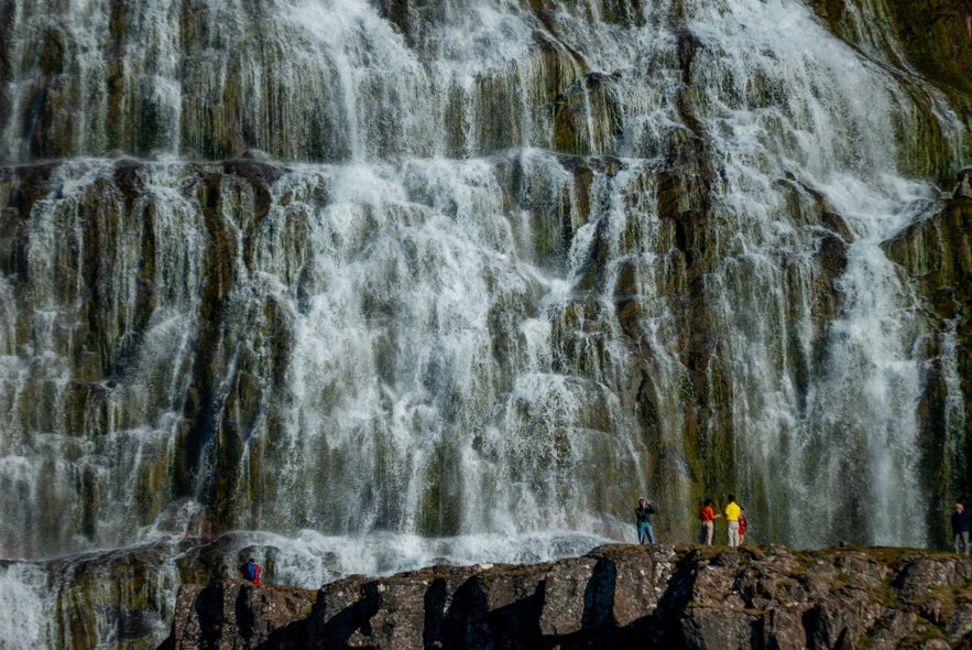 People admiring the giant Dynjandi Waterfall in the Westfjords of Iceland