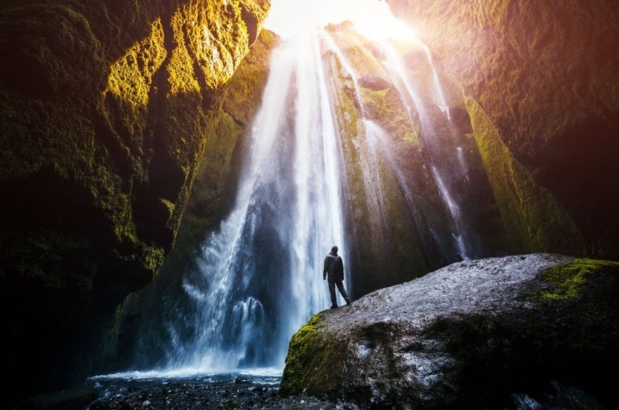 A person admiring Glufrabui, a hidden waterfall next to Seljalandsfoss Waterfall