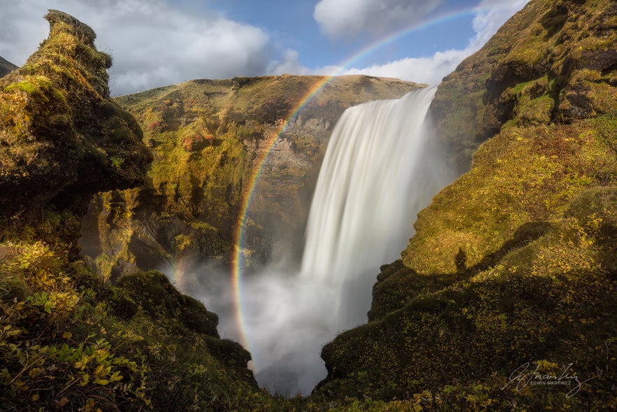Skogafoss Waterfall with rainbow seen from the staircase, which leads to the mountain side top