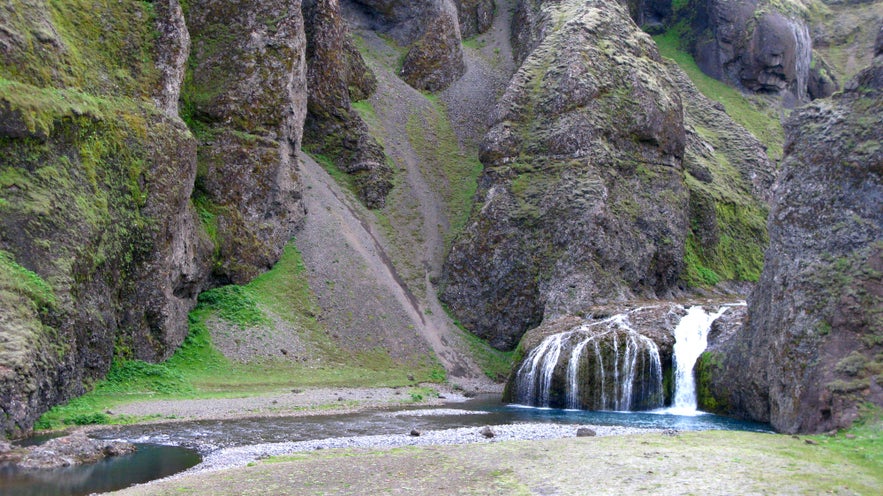 Stjornarfoss waterfall is surrounded by stunning volcanic rocks and formations.