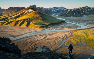 Hiker exploring the colorful rhyolite mountains in Landmannalaugar in Icelandic Highlands.