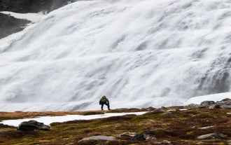 A person stands near the bottom of Dynjandi Waterfall in Iceland.
