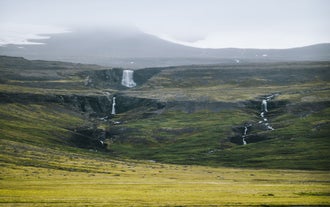 Waterfalls flow down a hillside in the Westfjords of Iceland, with streams cutting through the terrain.
