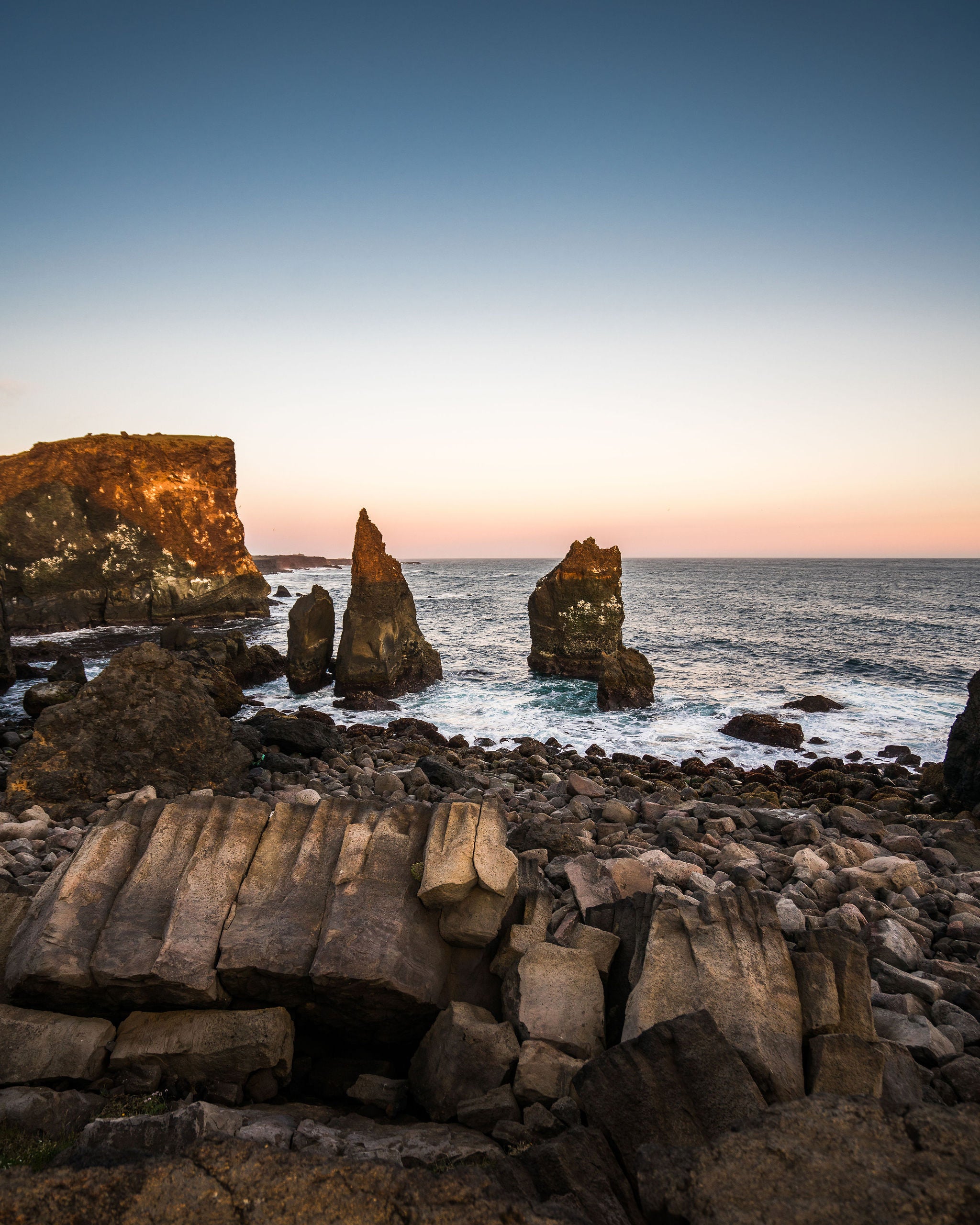 Rugged cliffs and sea stacks along the Reykjanes Peninsula coast at dusk.