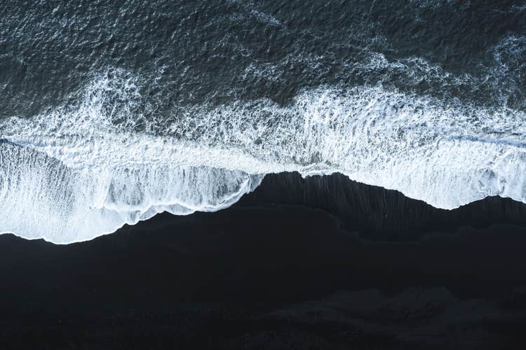 Waves crash against a black sand shore in Iceland.