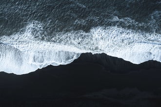 Waves crash against a black sand shore in Iceland.