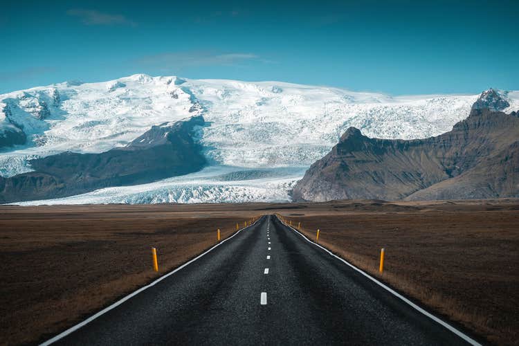 Road leading toward Vatnajokull Glacier with rugged mountains and snowy peaks along Iceland’s South Coast.