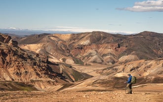 Hiker overlooking the colorful rhyolite mountains of Landmannalaugar in Iceland’s highlands.